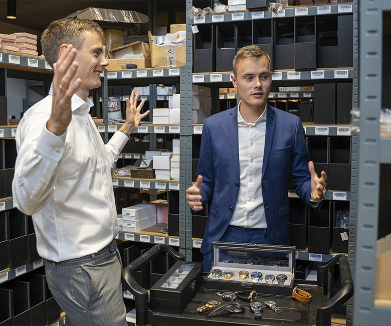 Kasper and Mikkel standing in the warehouse with watch boxes and watches